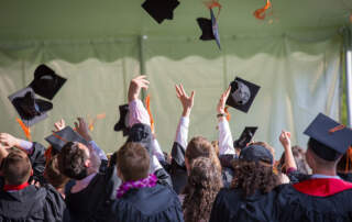 Students graduating throw their caps in the air in celebration. Recent Graduates can use their experience using WebCheckout to bring value to their next job.
